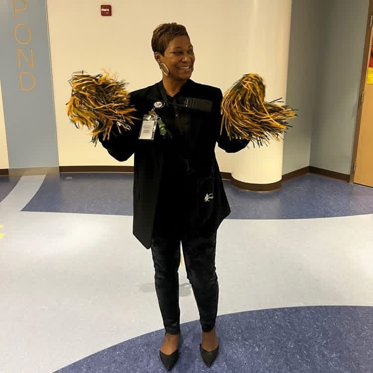 Ms. Baker-Hardison proudly cheering for GBP with green and gold pom poms