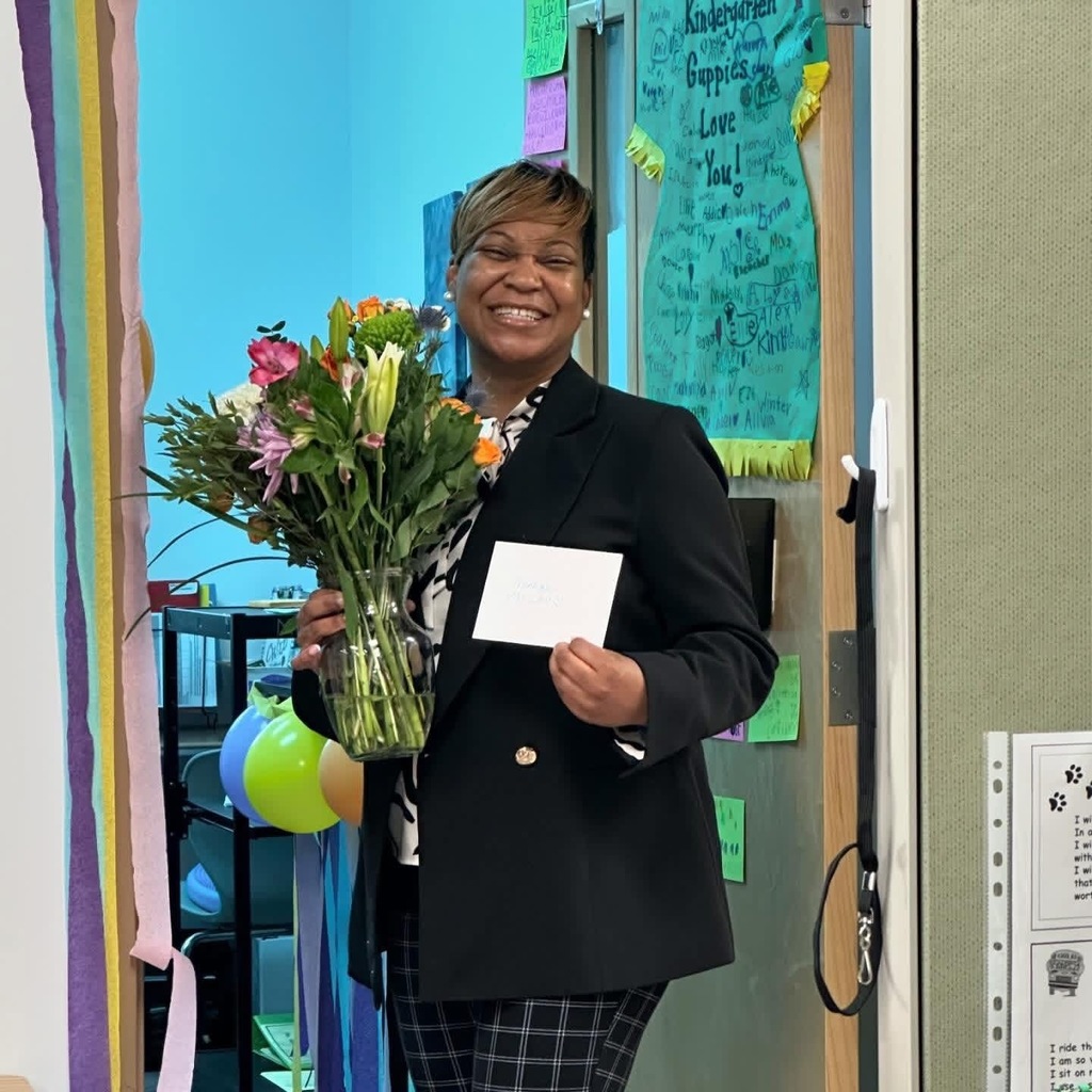 Ms. Baker-Hardison posing with a bouquet of flowers and a card