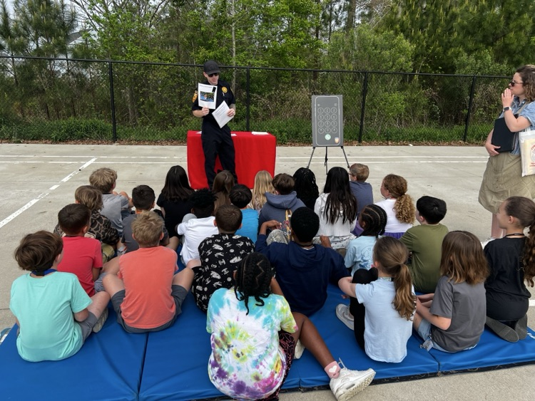 third graders, listening to firefighters speak to them about fire safety.