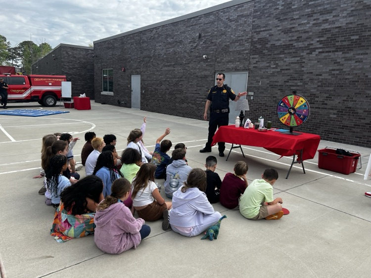third graders, listening to firefighters speak to them about fire safety.
