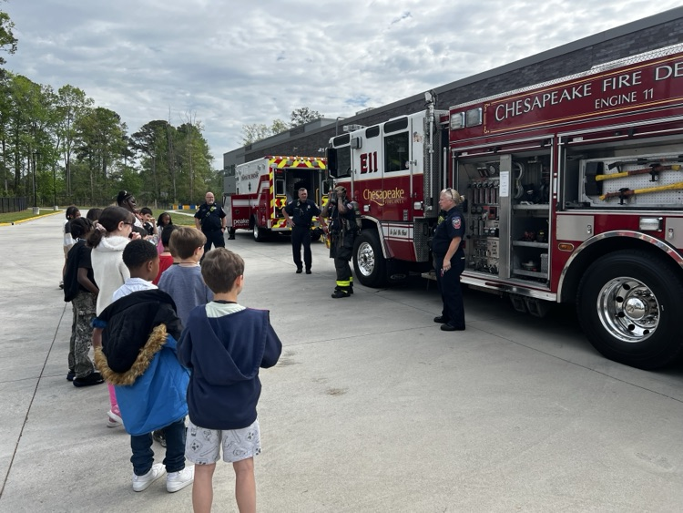 third graders, listening to firefighters speak to them about fire safety.