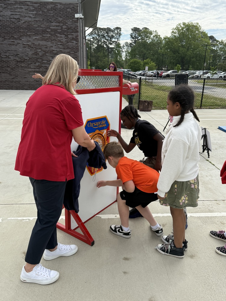 third graders, listening to firefighters speak to them about fire safety.