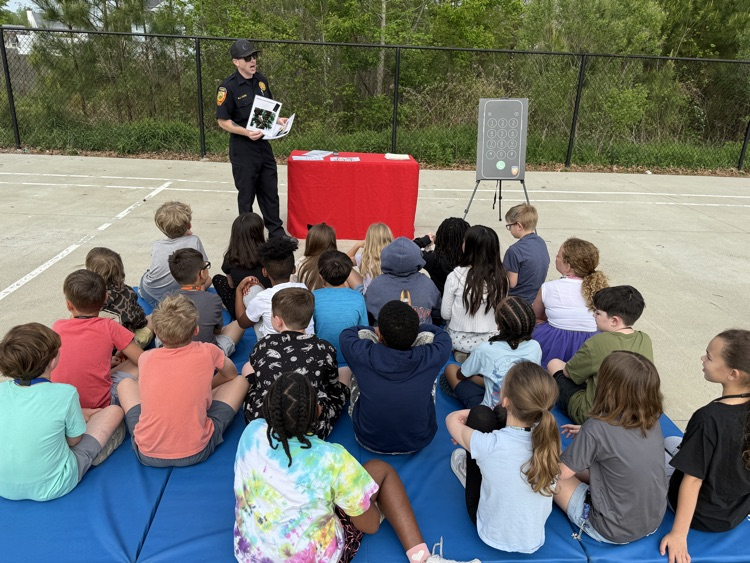 third graders, listening to firefighters speak to them about fire safety.
