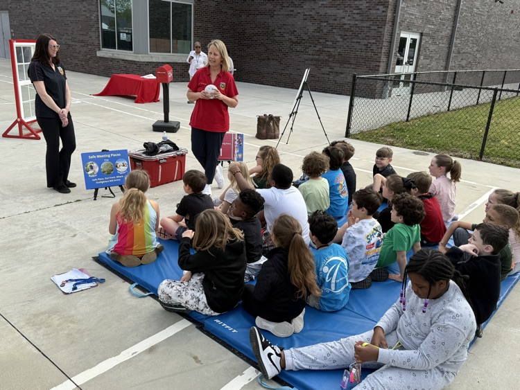 third graders, listening to firefighters speak to them about fire safety.