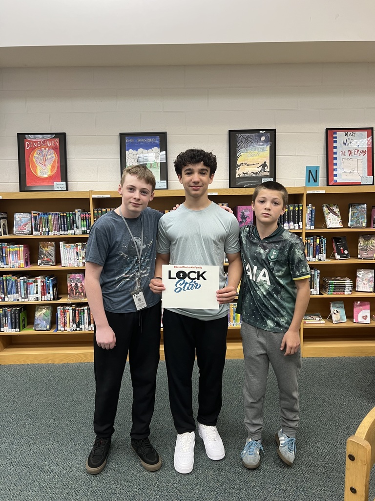 Students proudly holding a sign that shows they completed the escape room activity