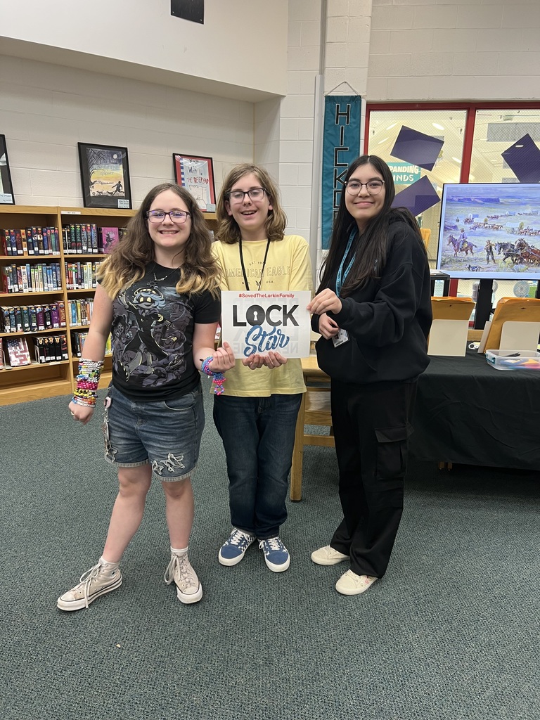 Students proudly holding a sign that shows they completed the escape room activity