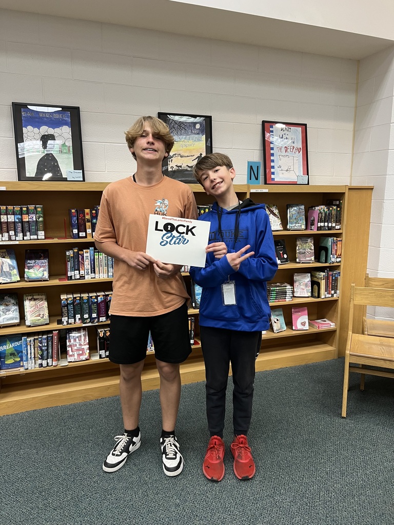 Students proudly holding a sign that shows they completed the escape room activity