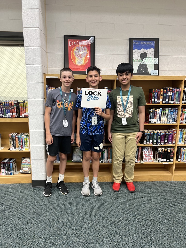 Students proudly holding a sign that shows they completed the escape room activity