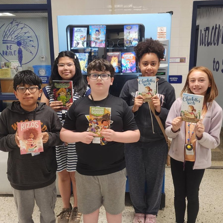 students proudly holding up their books they earned for March Junior Brave of the Month.