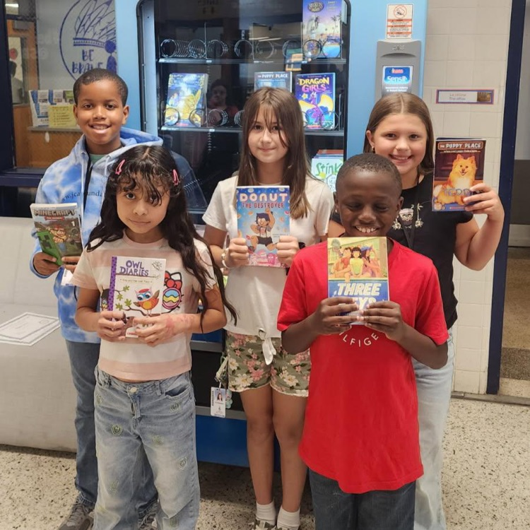 students proudly holding up their books they earned for March Junior Brave of the Month.