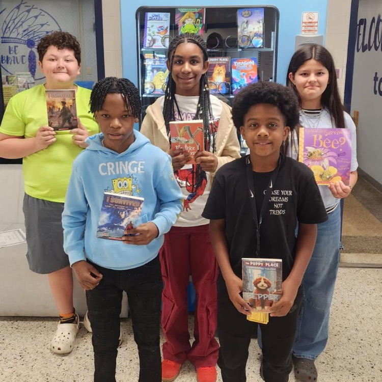 students proudly holding up their books they earned for March Junior Brave of the Month.