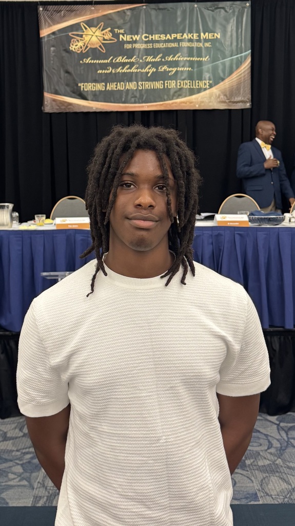 Middle school student stands confidently in front of a New Chesapeake Men for Progress Black Male Achievement Program banner, wearing a light shirt and looking directly at the camera