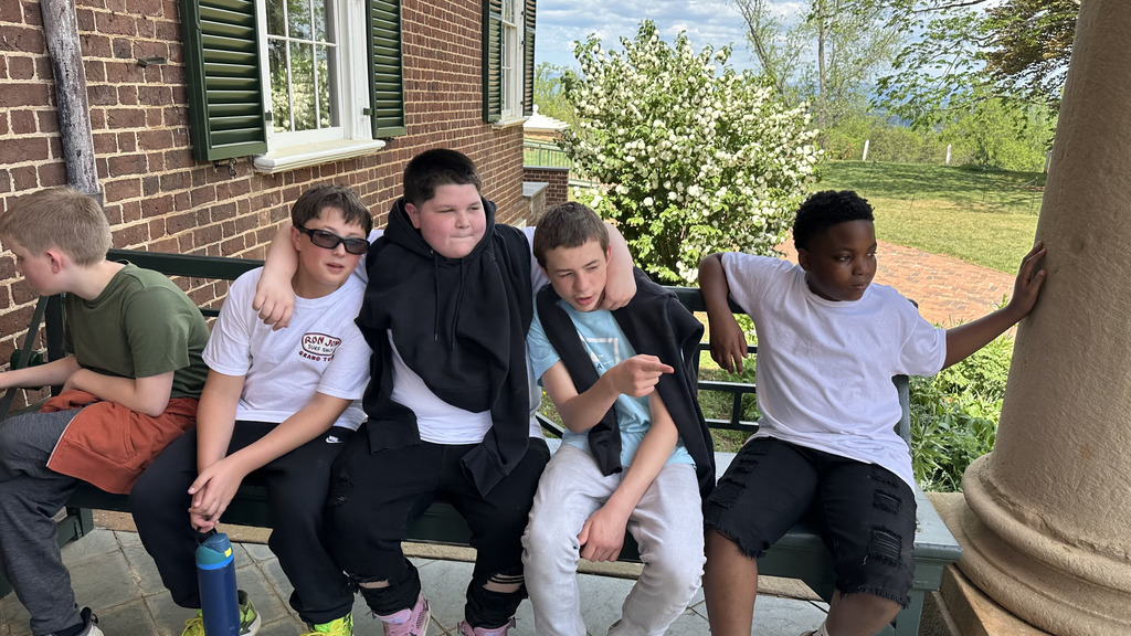 a group of students at Monticello relaxing on a bench on a beautiful day. 