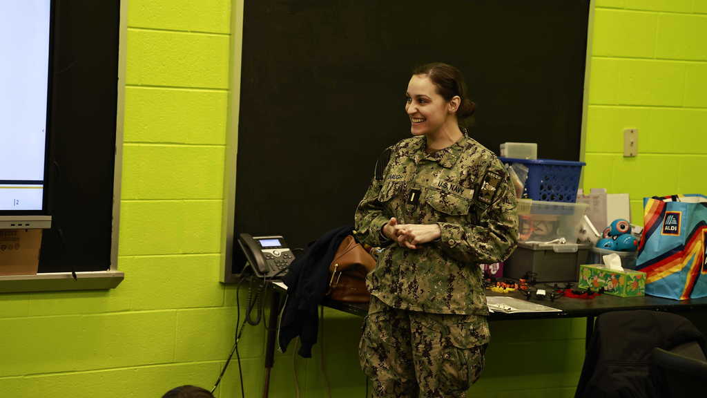 A member of the navy demonstrates a science lesson to students