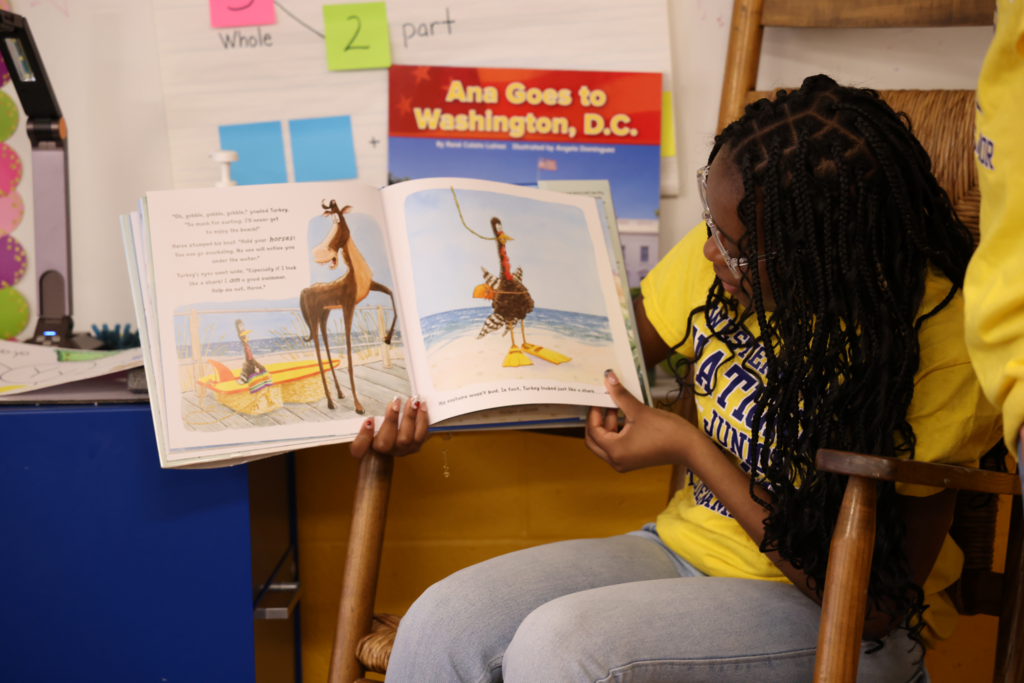 student excitedly reads to  primary students