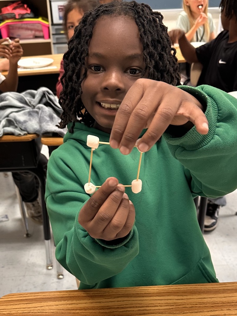 A Little Brave student holding his handmade 3D  shape made of marshmallows and toothpicks.