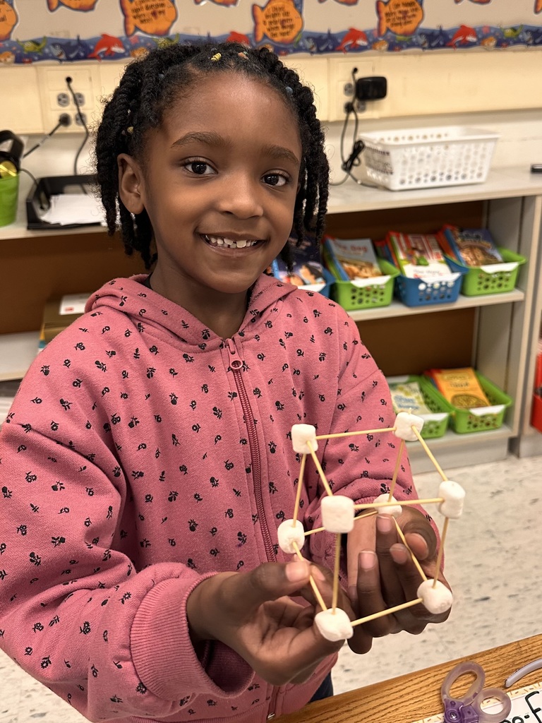A Little Brave student holding her handmade 3D  shape made of marshmallows and toothpicks.