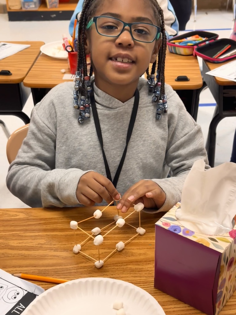 A Little Brave student holding her handmade 3D  shape made of marshmallows and toothpicks.