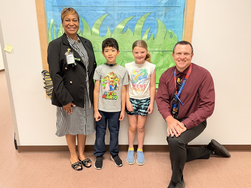 March Students of the Month pose with school administrators and smile for a group photo recognizing trustworthiness.