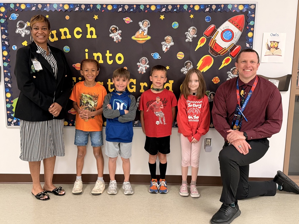 March Students of the Month pose with school administrators and smile for a group photo recognizing trustworthiness.