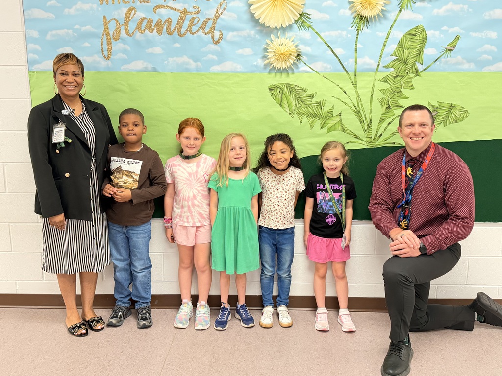March Students of the Month pose with school administrators and smile for a group photo recognizing trustworthiness.