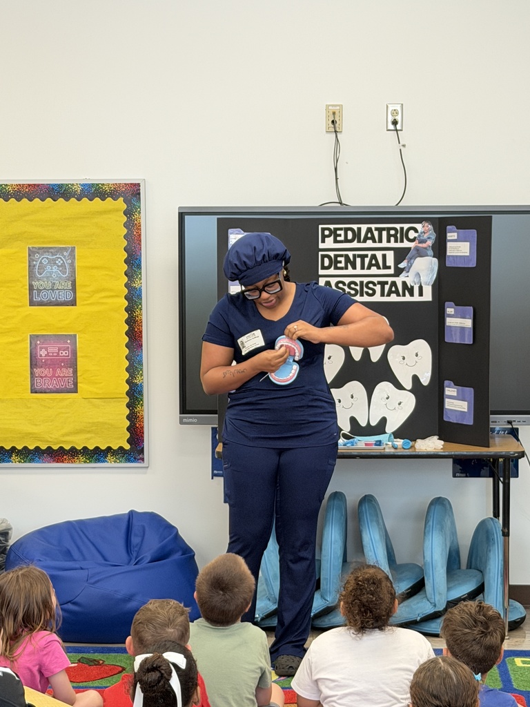 Dental hygienist visiting the school on Career Day, speaking with students and demonstrating dental tools while students watch and listen attentively.