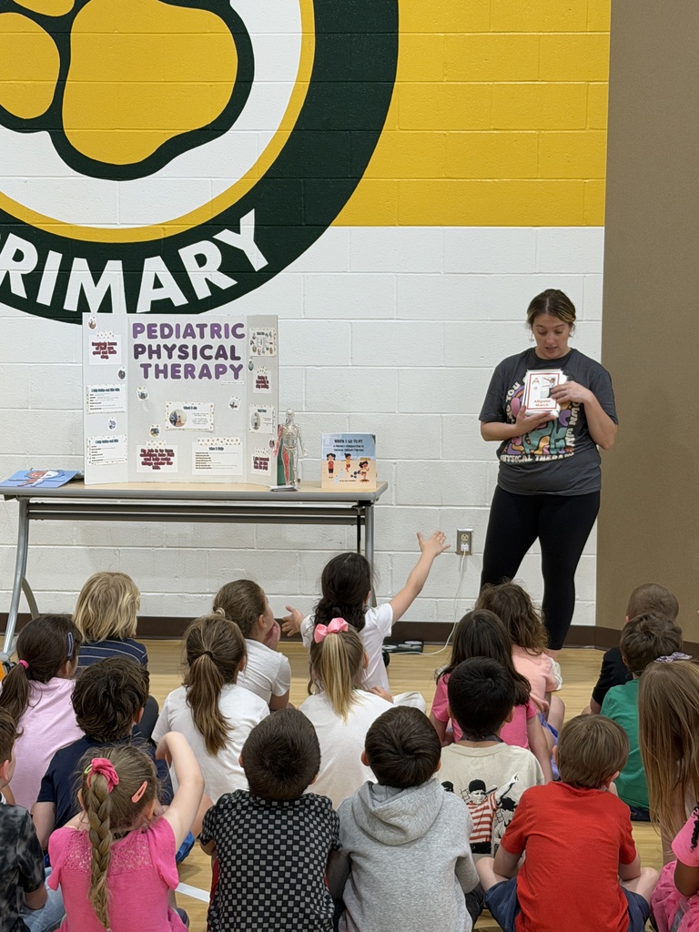 Pediatric physical therapist presenting to a class of students, sharing about her job, while they listen attentively.