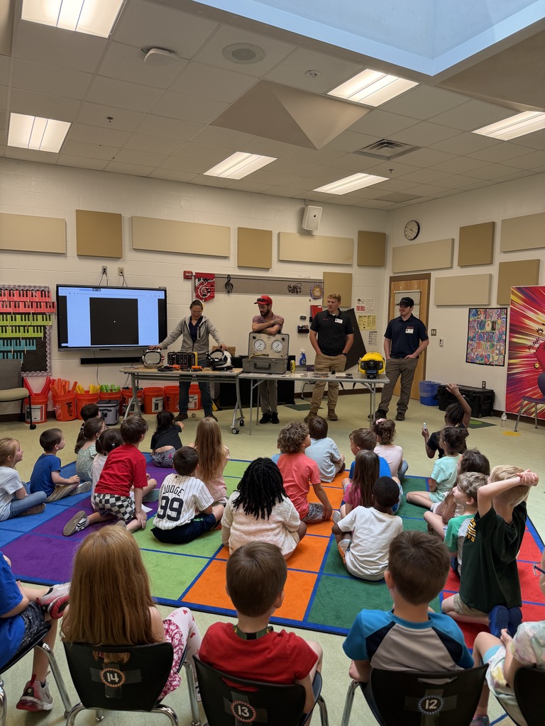 Crane divers presenting to a classroom of students during Career Day, standing at the front with their diving tools and materials displayed while students watch and listen attentively.