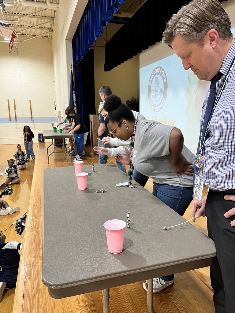 Staff and students competing on stage with cups and bolts.