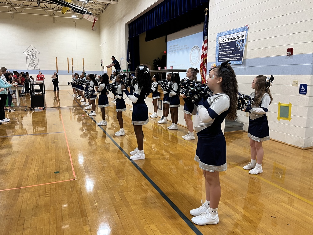 Cheerleaders up front by the stage with admin presenting.