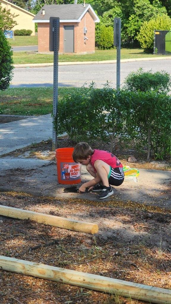 Child kneeling on the sidewalk cleaning up.