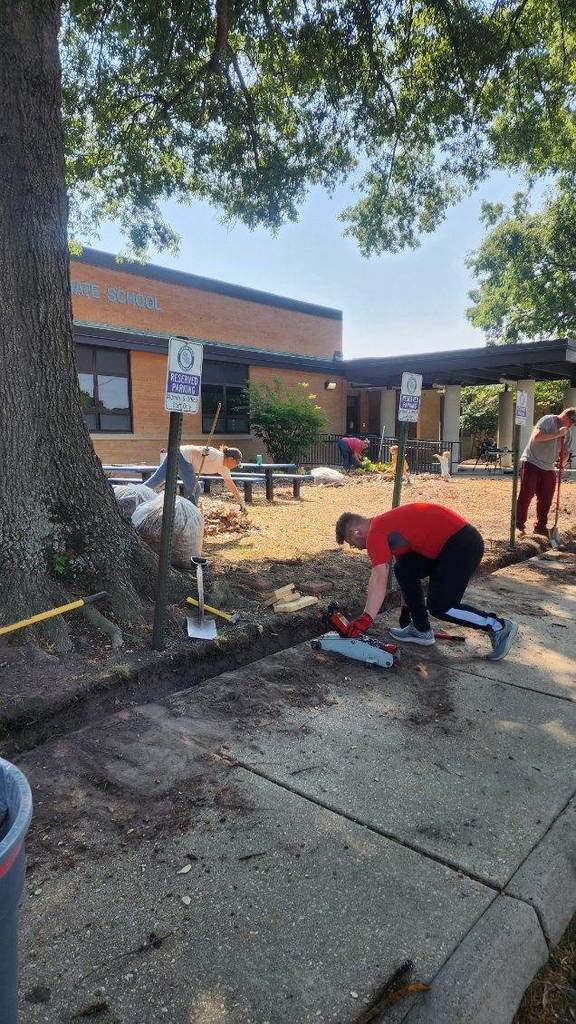 Community working on cleaning up the mulch area in front of the building.