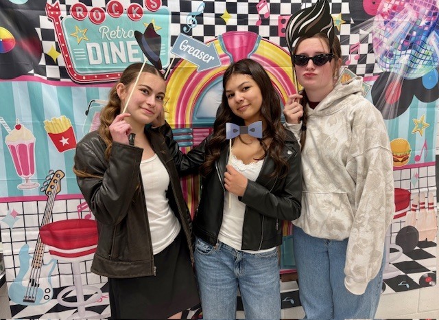 Students posing in front of a 1950s poster