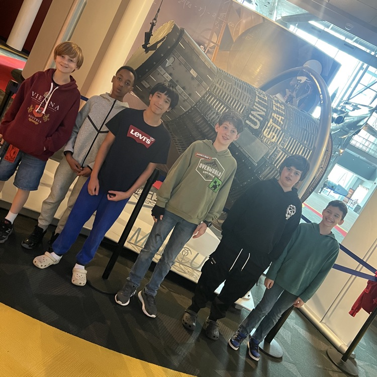 Boys smiling in front of space exhibit. 