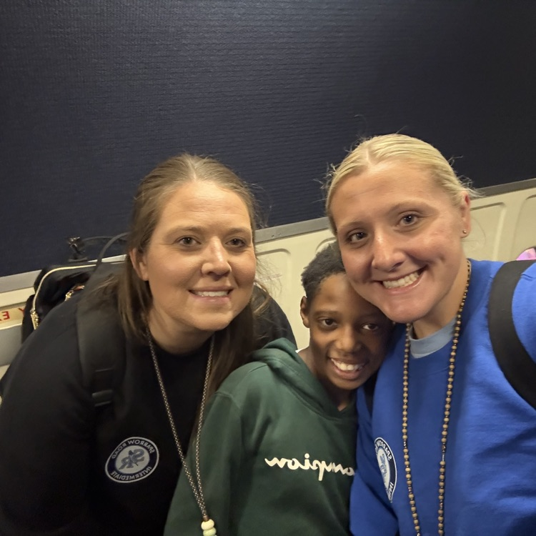 Teachers and student huddled together smiling for a selfie.