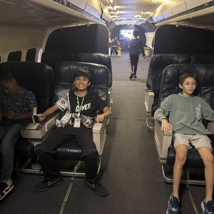 students sitting in some chairs inside a plane. 