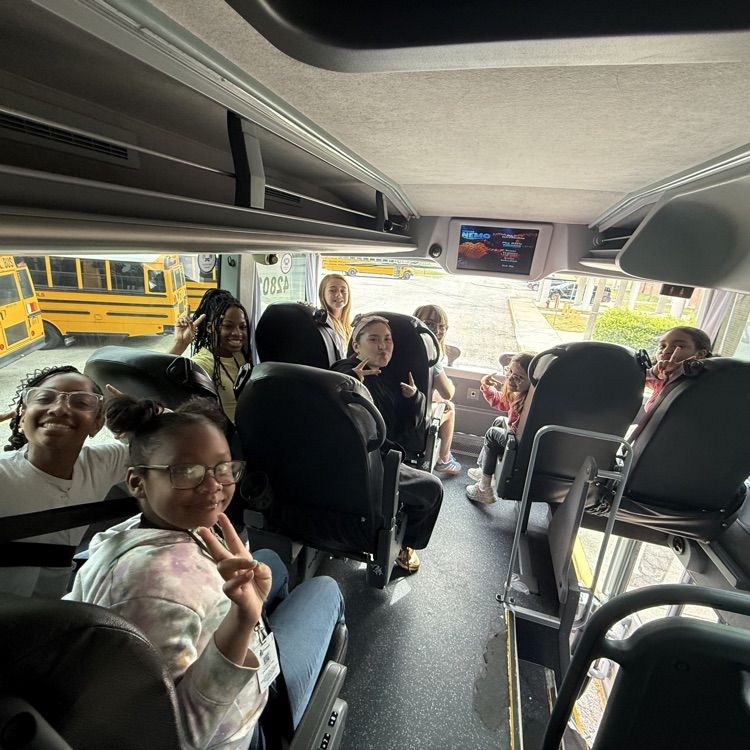 students on the bus smiling and excited for the field trip. 
