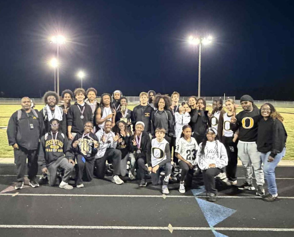 Track team standing on the field smiling 