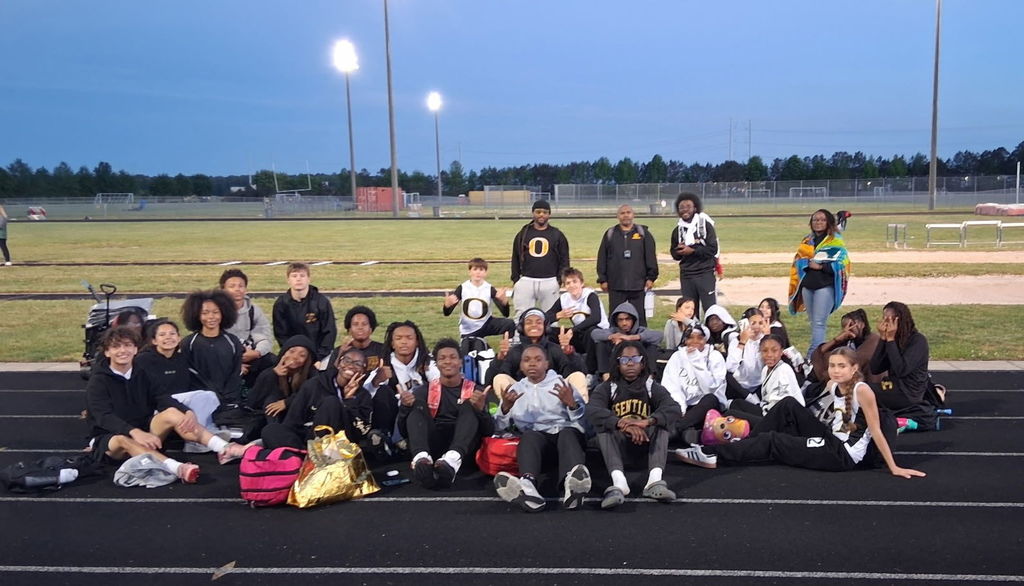 boys and girls track team sitting on field 