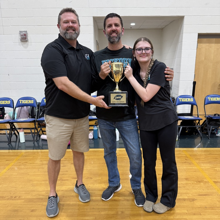 coaches proudly holding the city championship trophy