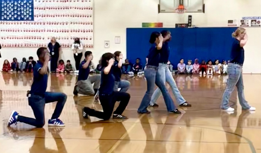 Indian River High School JROTC students in uniform leading an activity with a group of elementary students in the school gym.