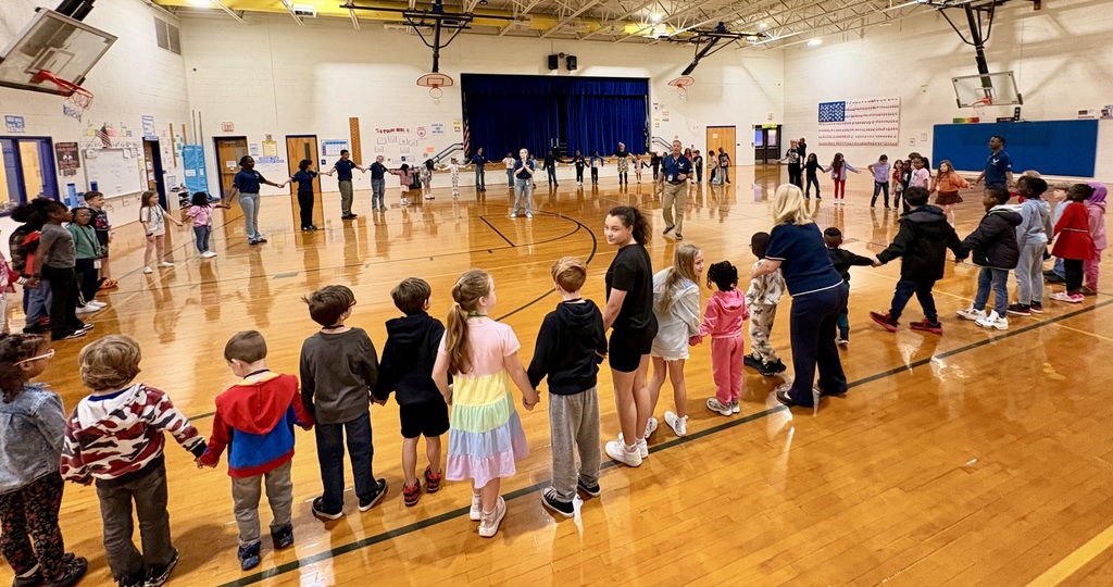 Indian River High School JROTC students in uniform leading an activity with a group of elementary students in the school gym.
