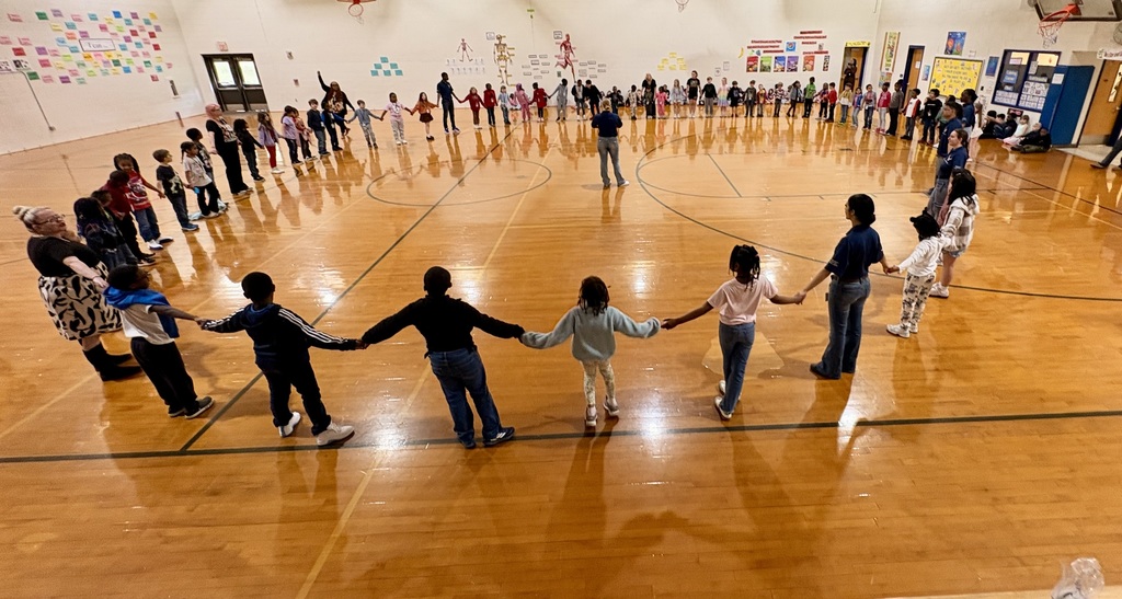 Indian River High School JROTC students in uniform leading an activity with a group of elementary students in the school gym.