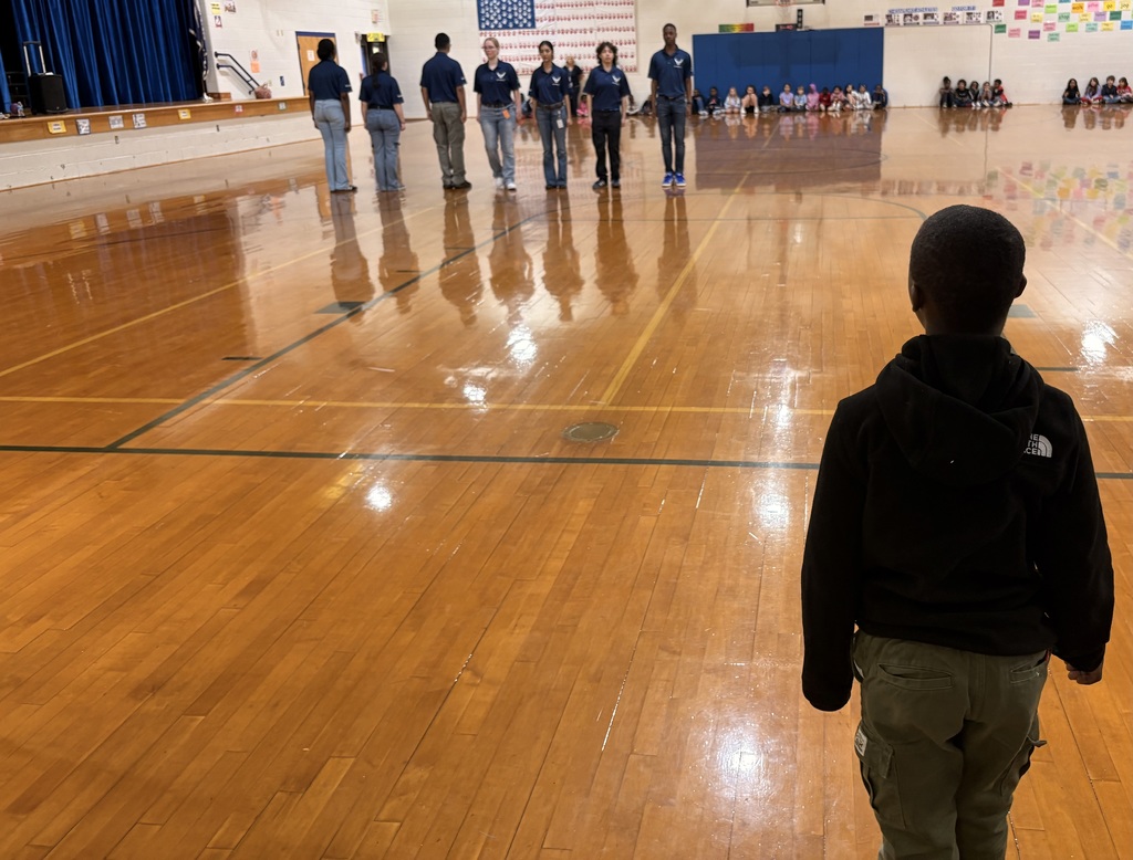 Indian River High School JROTC students in uniform leading an activity with a group of elementary students in the school gym.