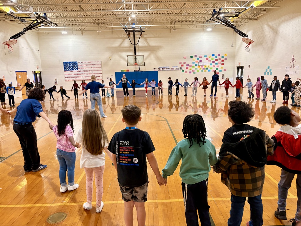 Indian River High School JROTC students in uniform leading an activity with a group of elementary students in the school gym.