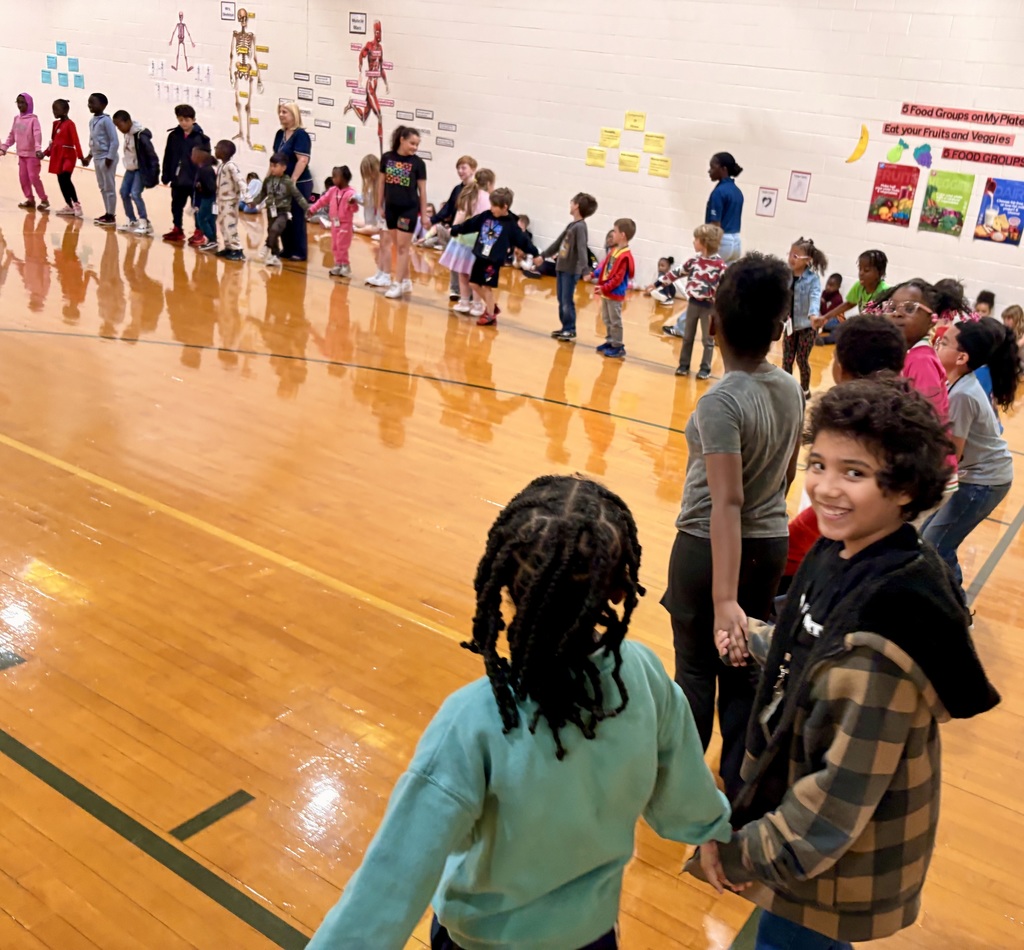 Indian River High School JROTC students in uniform leading an activity with a group of elementary students in the school gym.