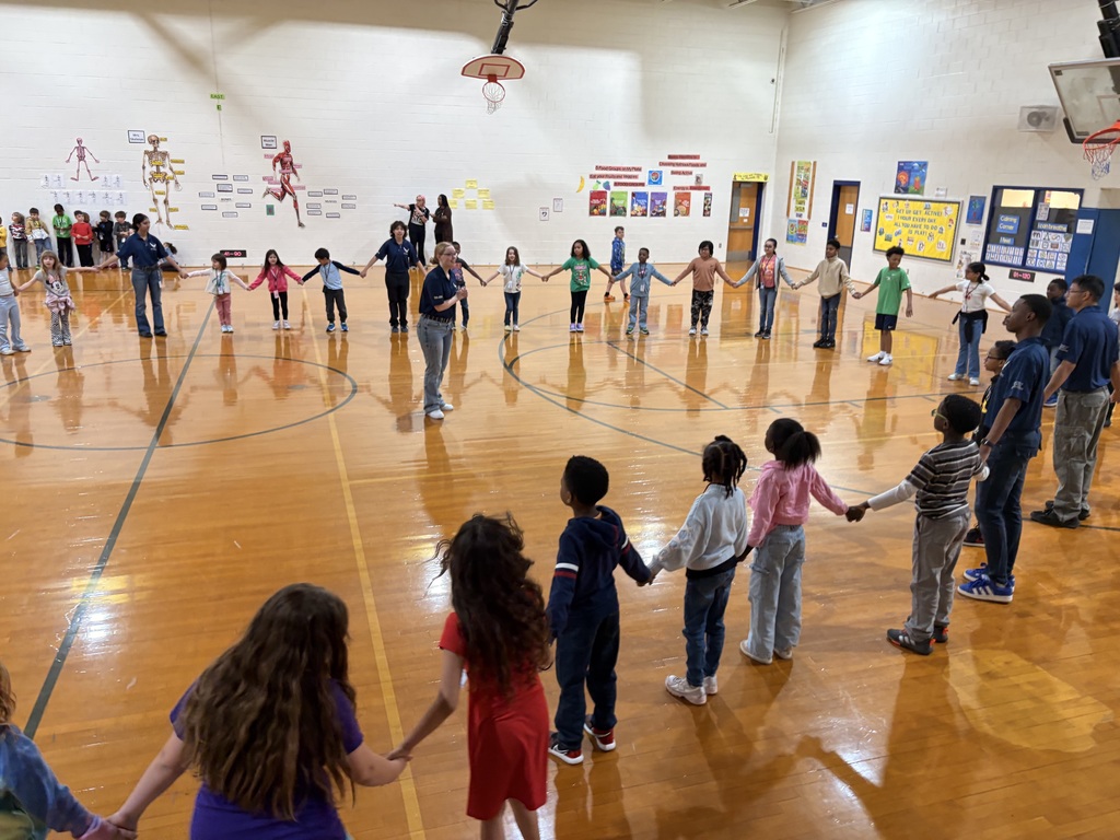 Indian River High School JROTC students in uniform leading an activity with a group of elementary students in the school gym.