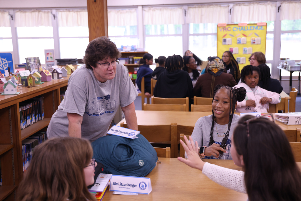 A teacher interacting with happy students.