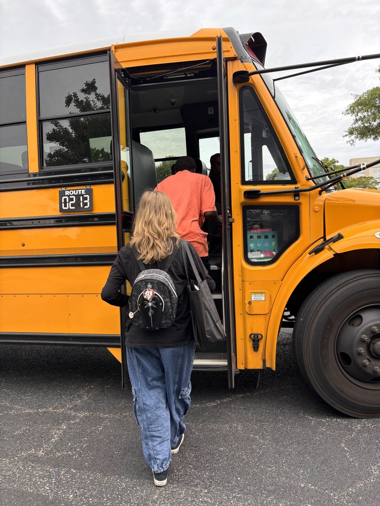 back of two students getting on yellow school bus 