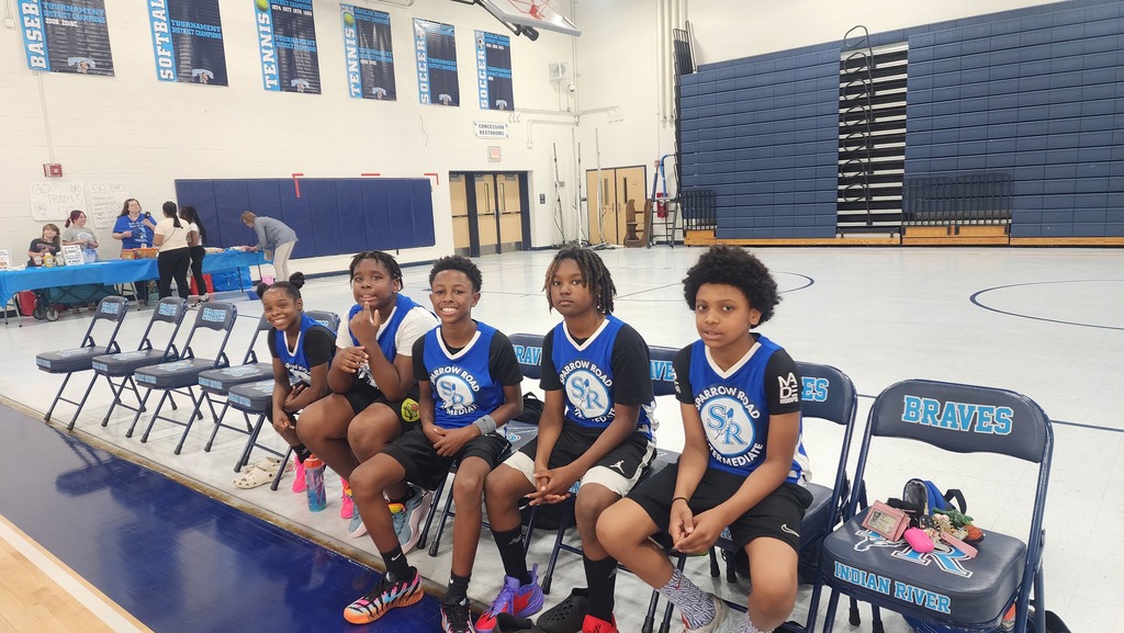 Some of the SRI Student basketball team sitting in chairs smiling.